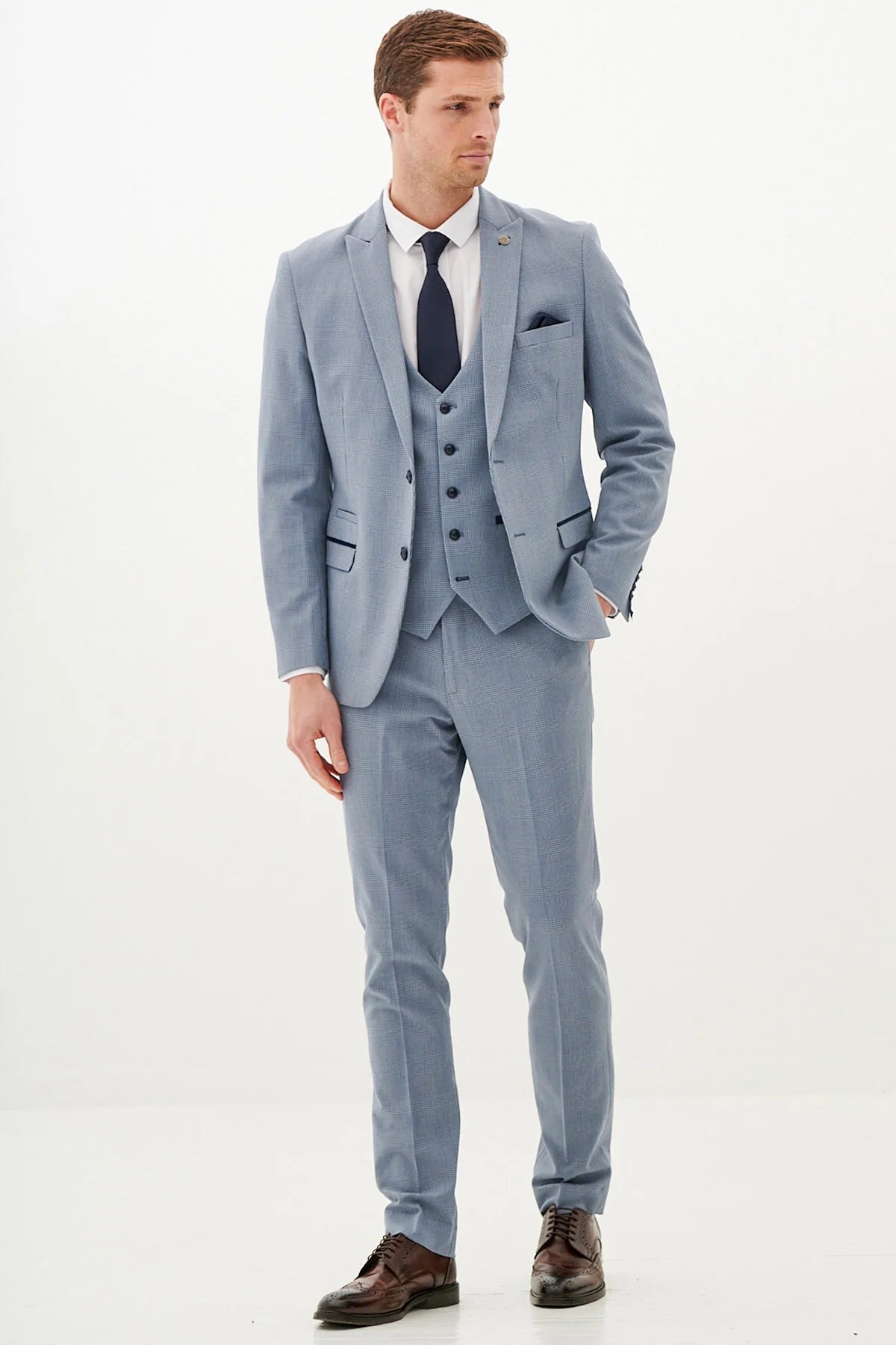 A man modeling a sky blue check three piece suit with a waistcoat, tie, and pocket square.