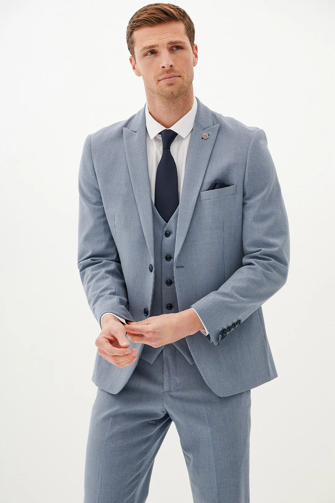 Man wearing a light blue suit with a black tie on a plain background