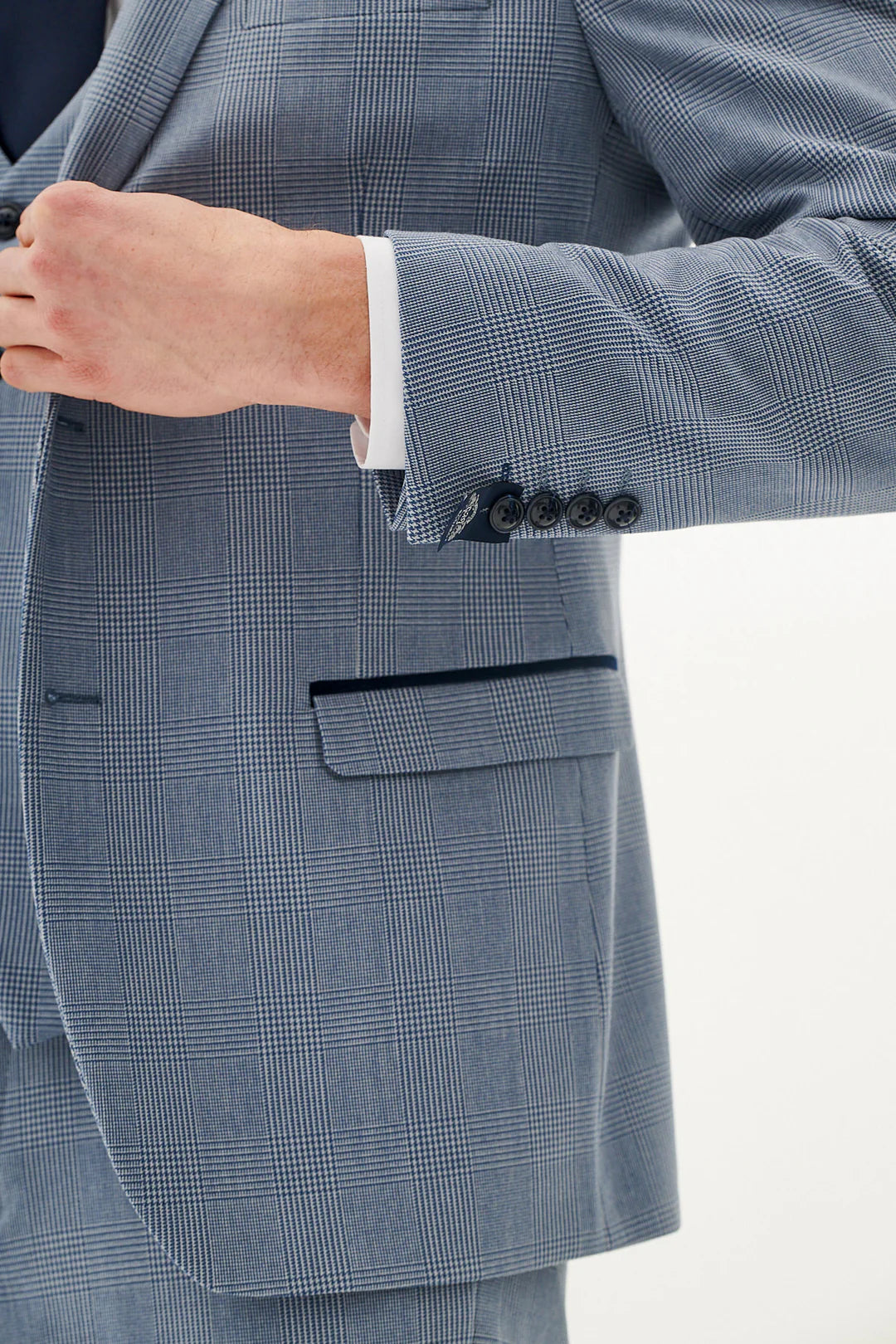 Close-up of a blue checkered suit jacket with a hand adjusting the cuff.