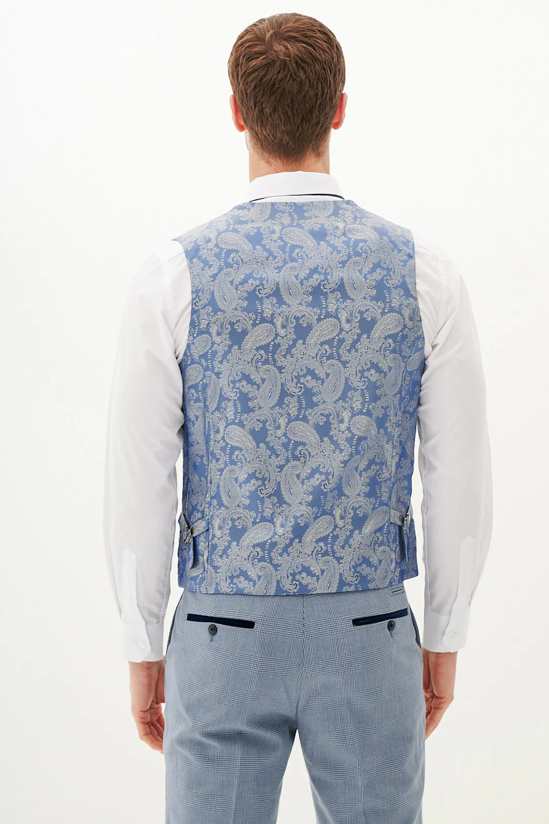 Man wearing a blue paisley vest and light blue pants on a white background.