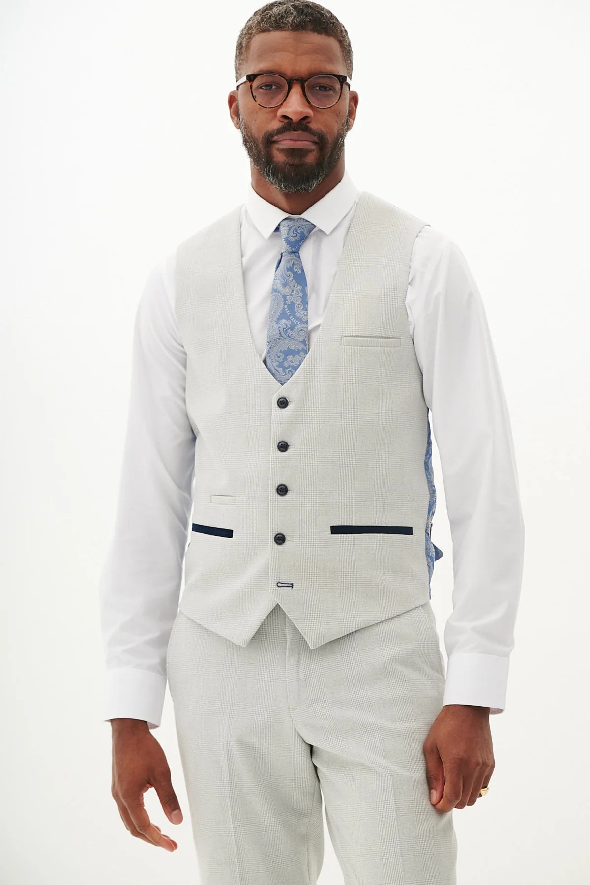 Man wearing a light gray vest and tie on a white background