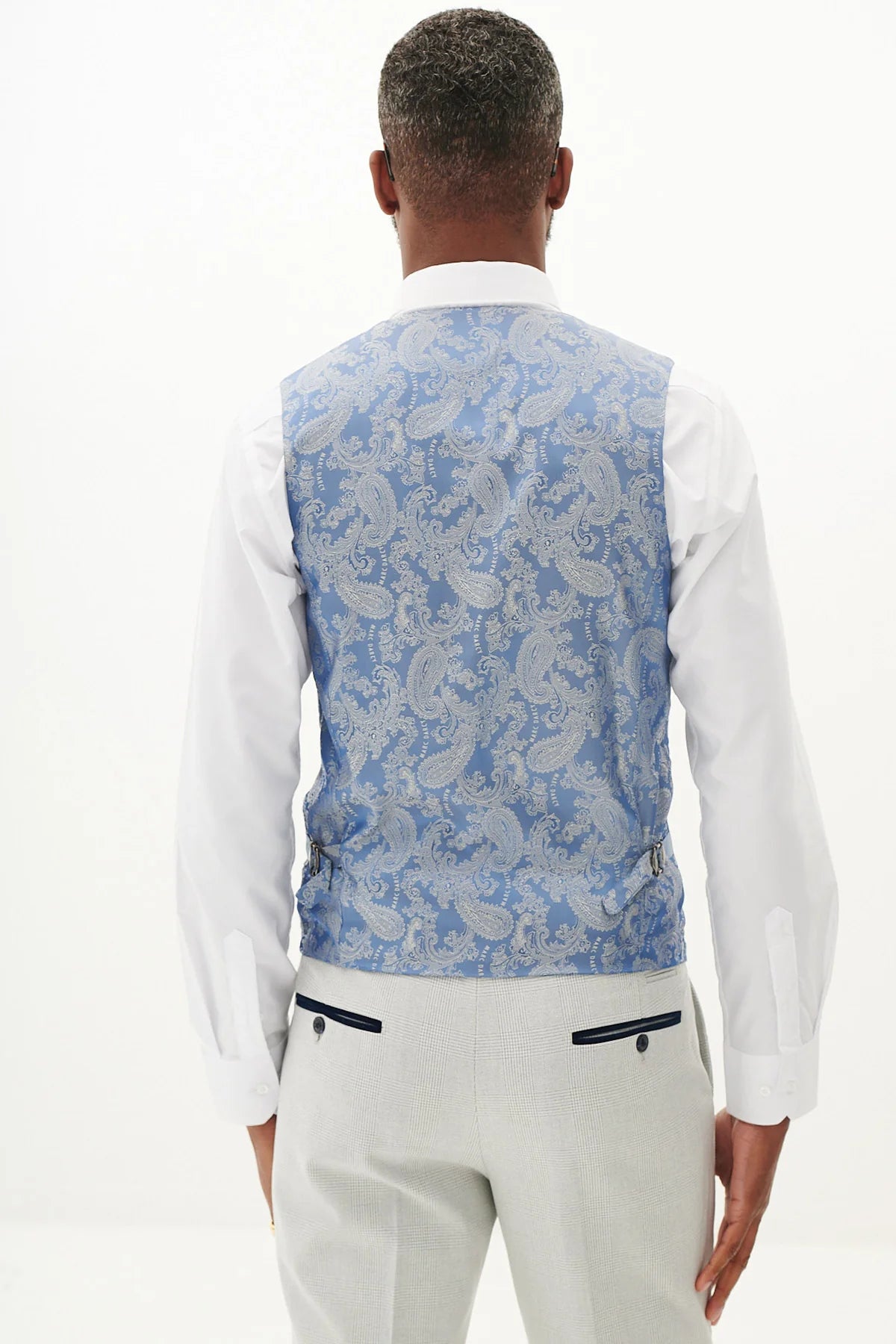 Person wearing a blue paisley vest over a white shirt.