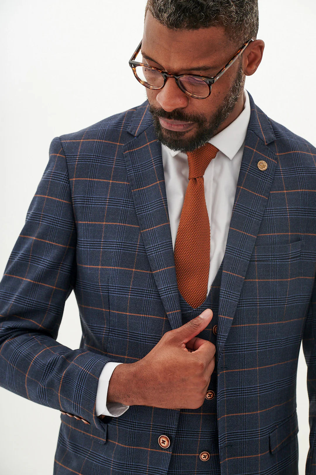 Man wearing a blue checkered suit with a brown tie.