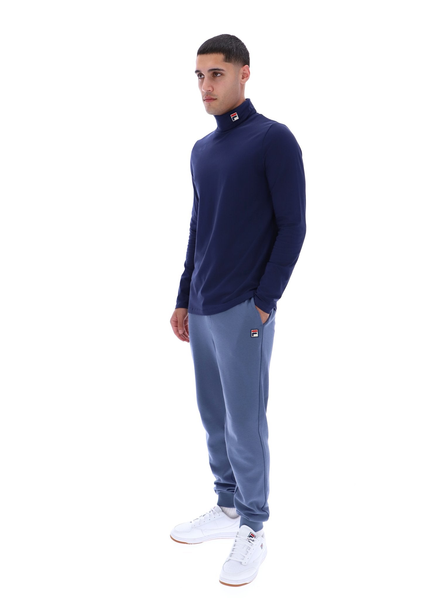 Man wearing a navy sweater and gray pants on a white background
