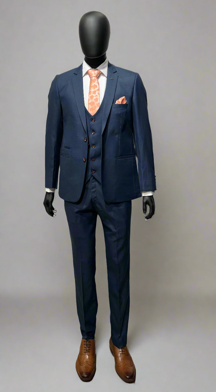 A navy three-piece suit on a mannequin, including a jacket, waistcoat, and trousers, complemented by a white shirt and brown shoes.