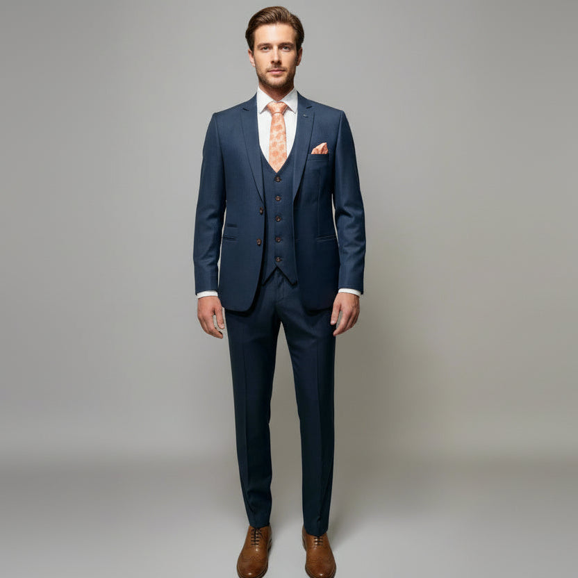 A navy three-piece suit on a mannequin, including a jacket, waistcoat, and trousers, complemented by a white shirt and brown shoes.