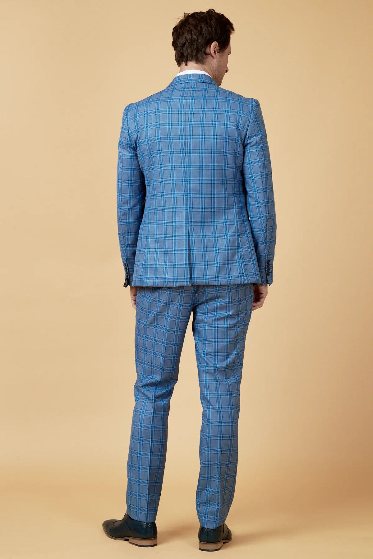 Man wearing a blue checkered suit against a beige background