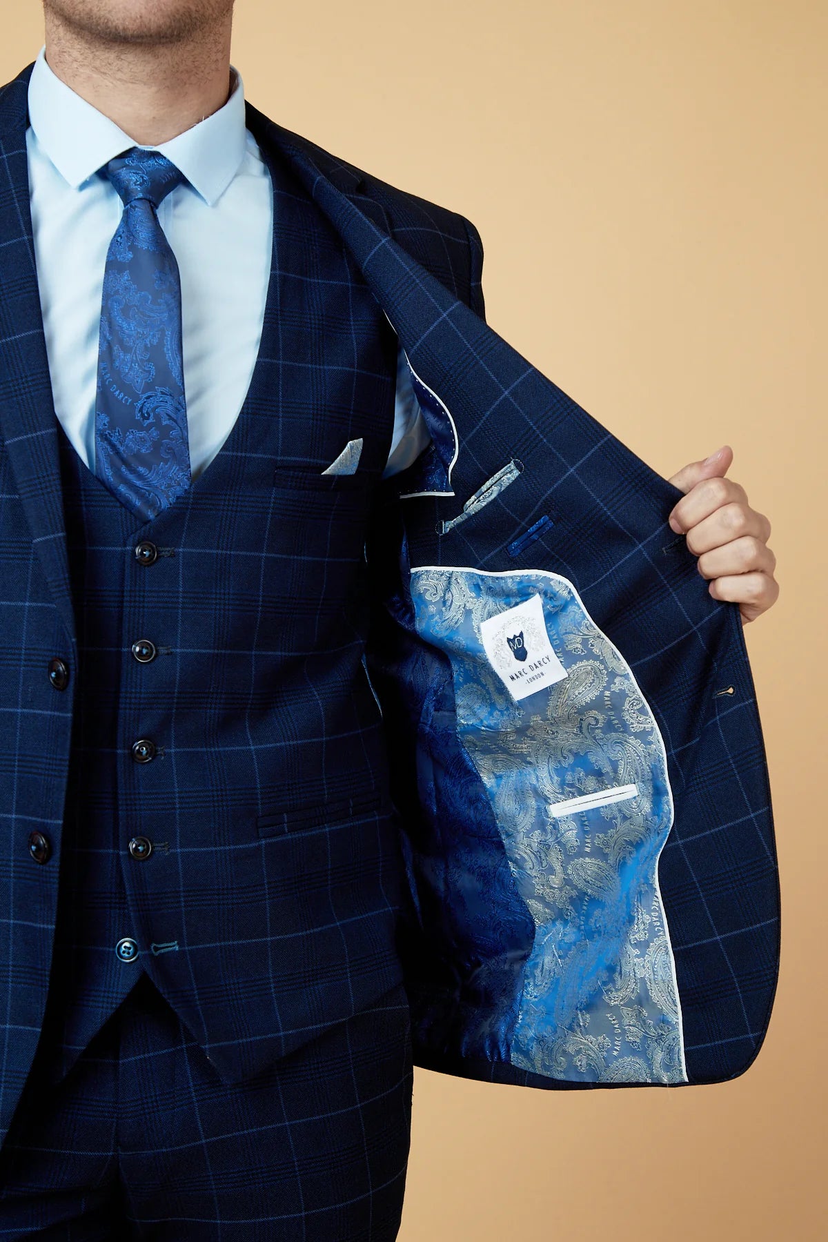 Person holding a blue suit jacket with a plain background