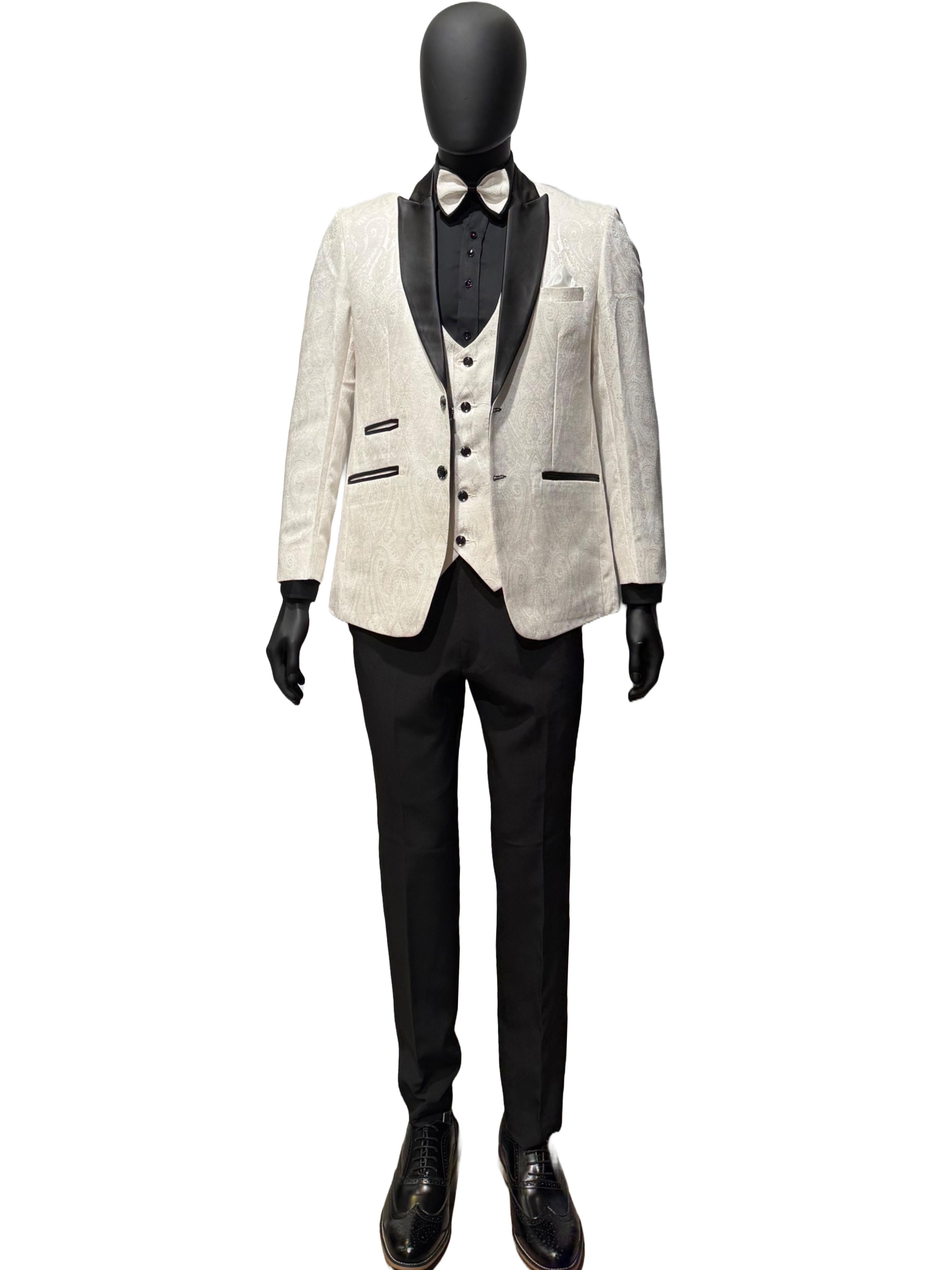 A mannequin displaying an off white tuxedo suit with black trousers, a bow tie, and black shoes.