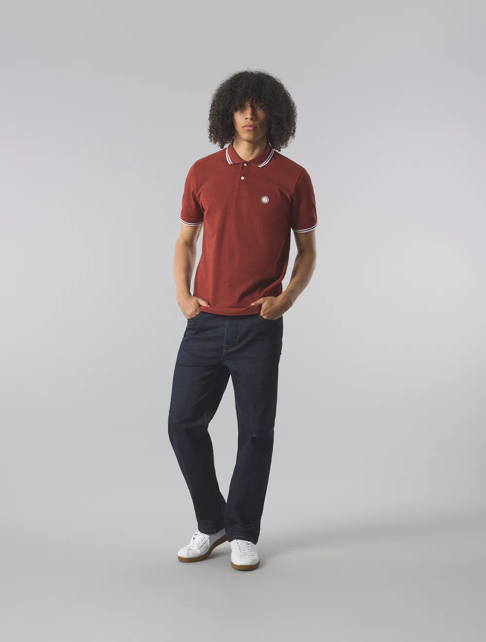 Person wearing a red polo shirt and dark pants on a gray background