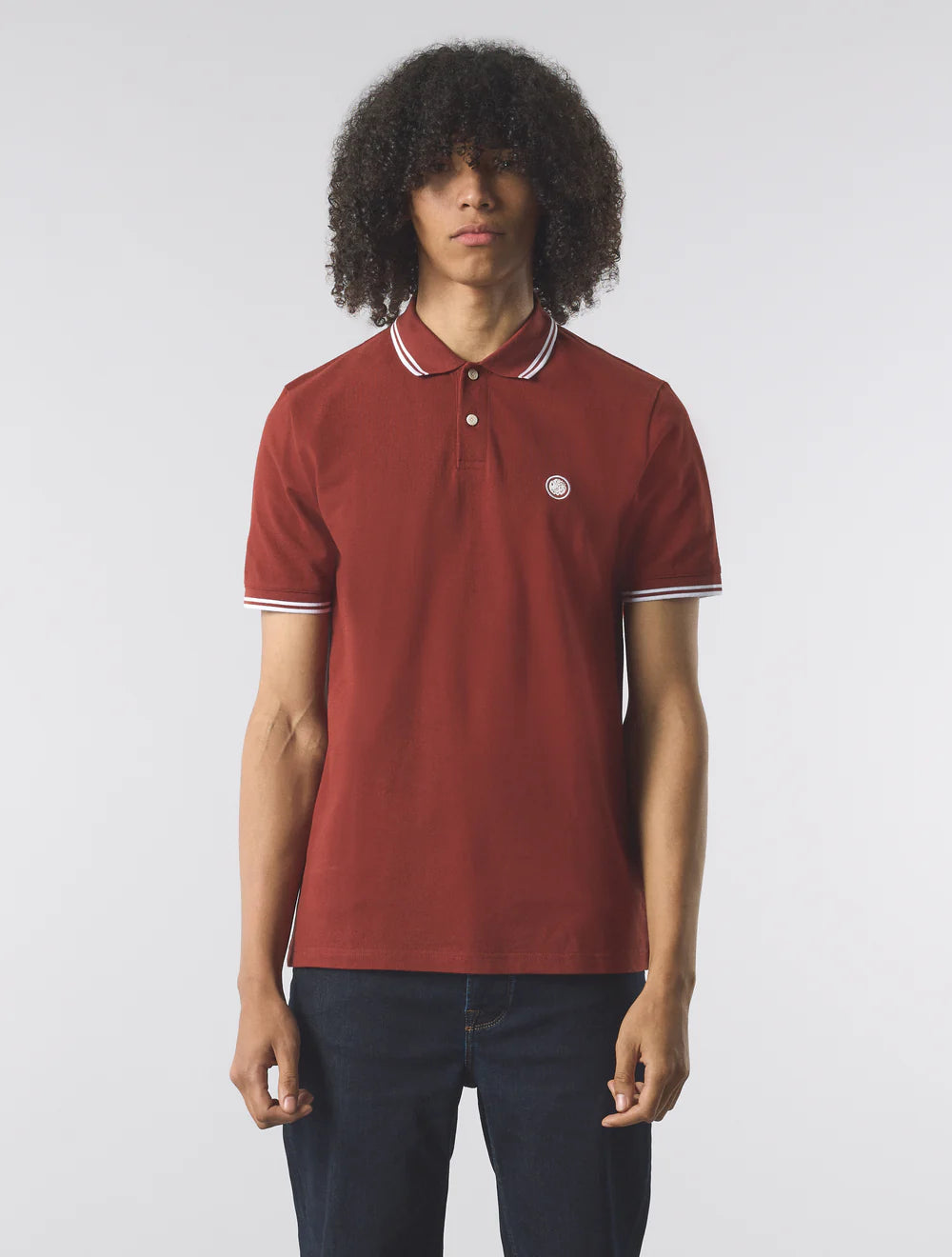 Person wearing a red polo shirt with white trim on a plain background