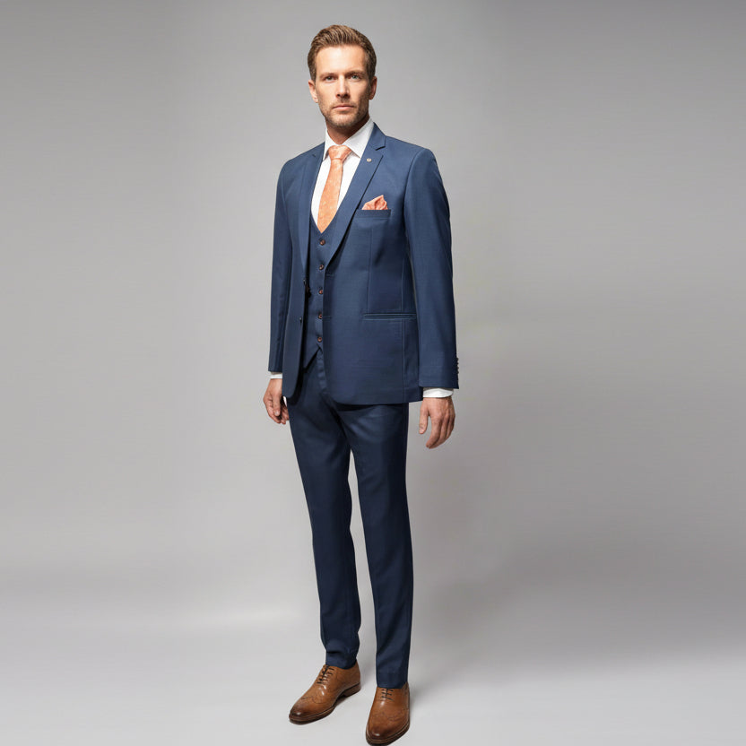 Navy blue suit with a white shirt, orange tie, and brown shoes on a gray background