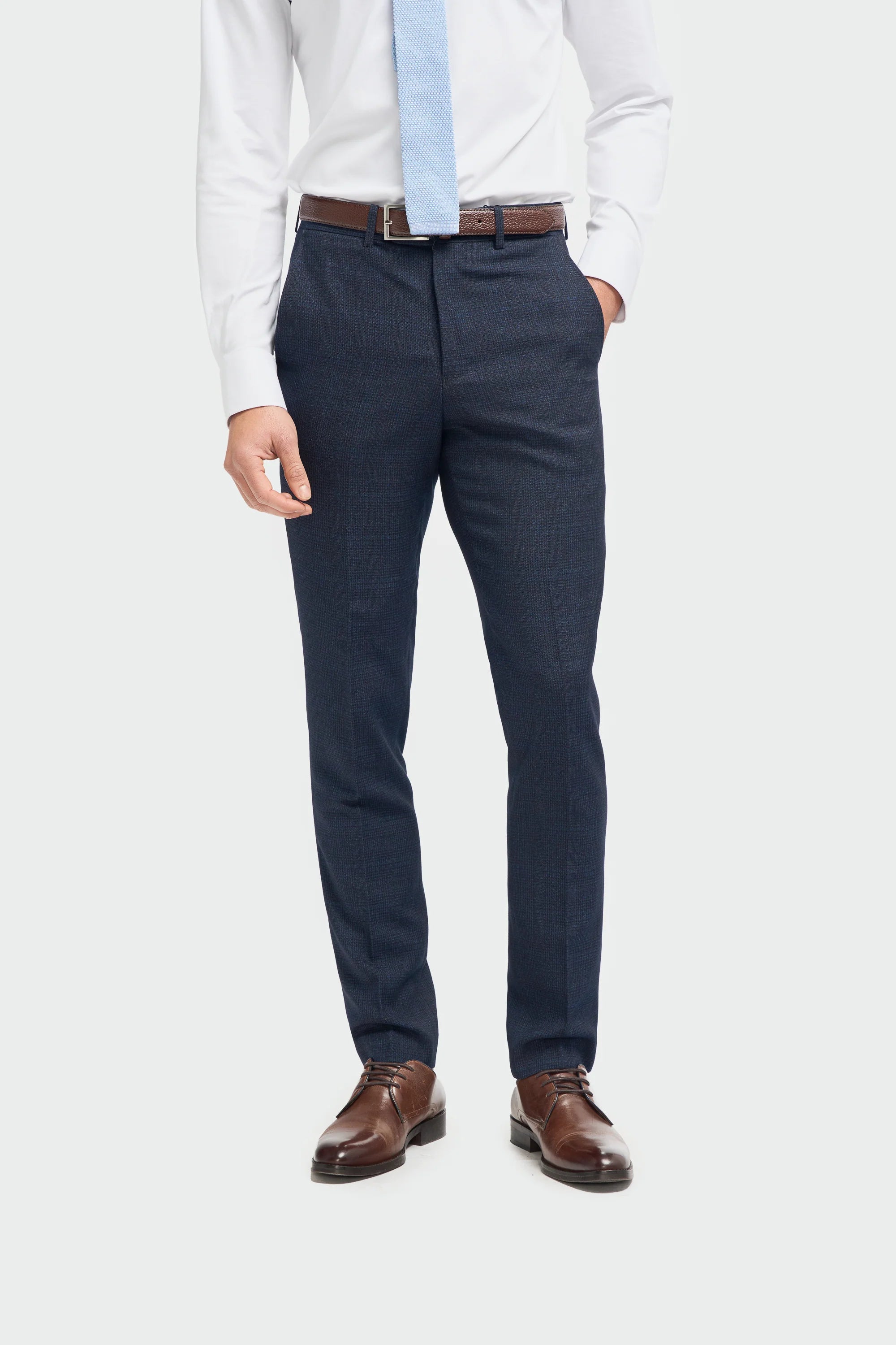 A male model wearing a House Of Cavani Caridi Navy Three Piece Suit with a deep navy color, tailored fit, and a regular length. The model is also wearing a white shirt and brown shoes.