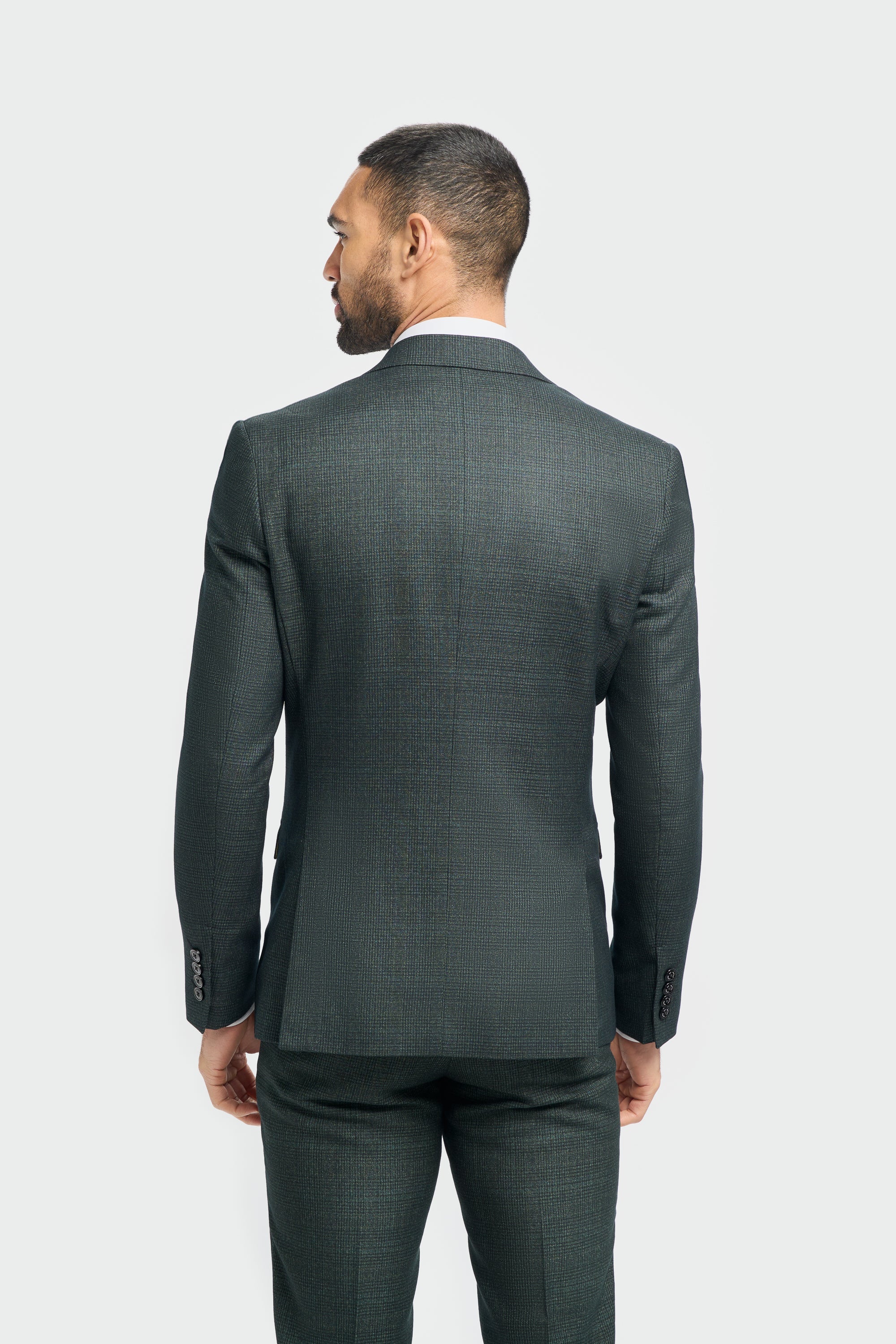 Man wearing a dark green suit on a plain background