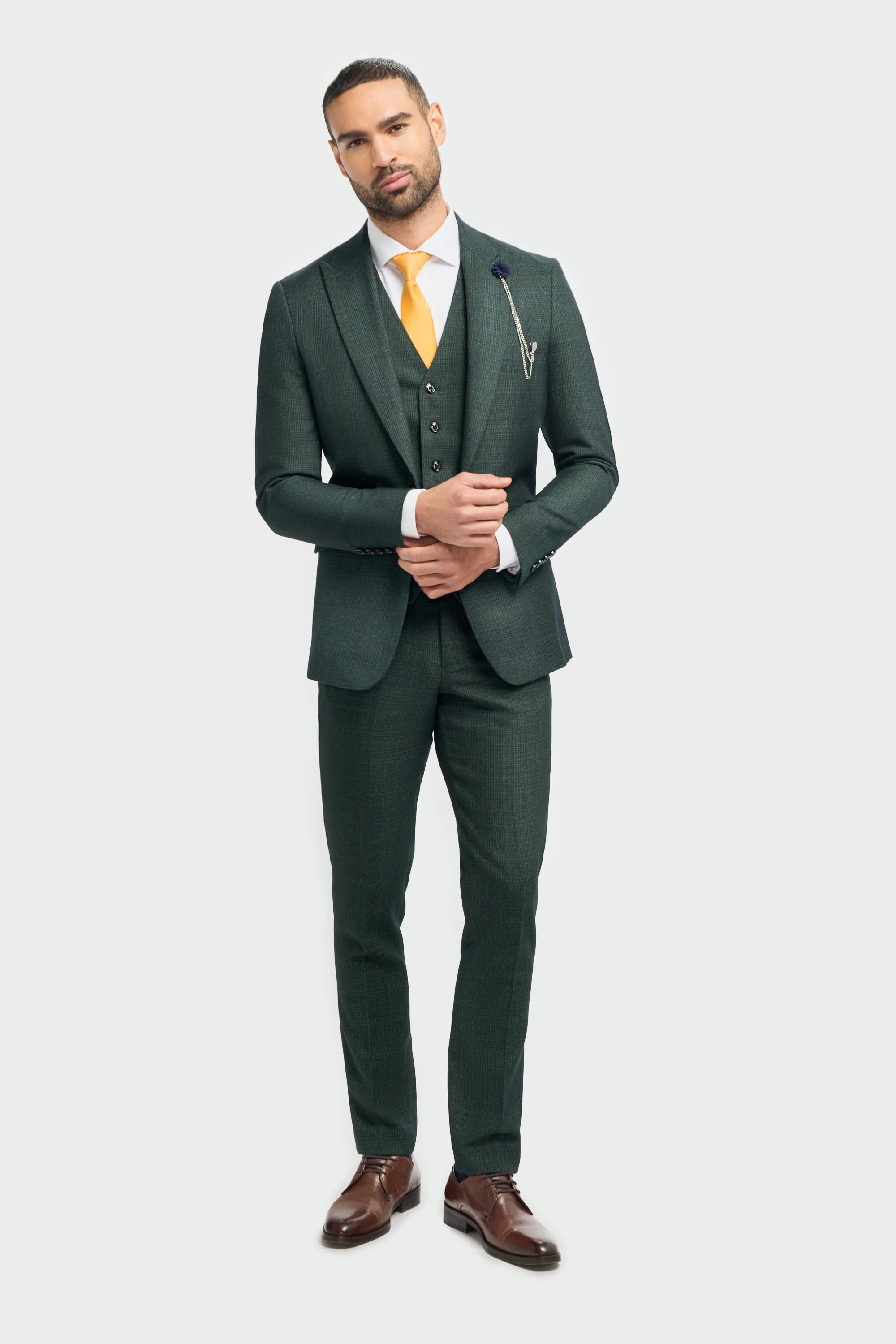 A male model wearing a Caridi Olive Check Three Piece Suit with a tailored blazer, sharp waistcoat, and trousers in a rich olive color.