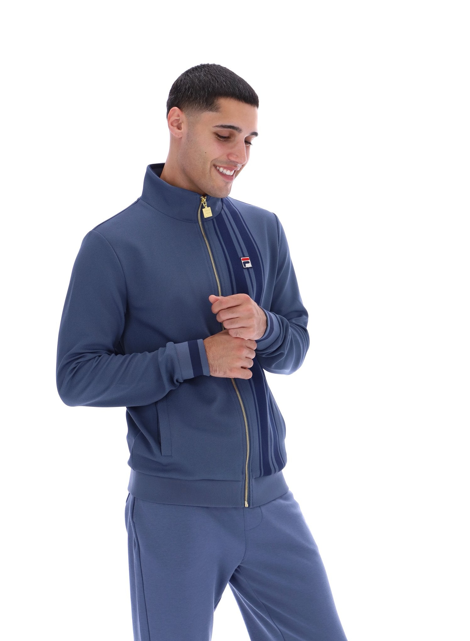 Man wearing a blue tracksuit with a visible brand logo on a white background