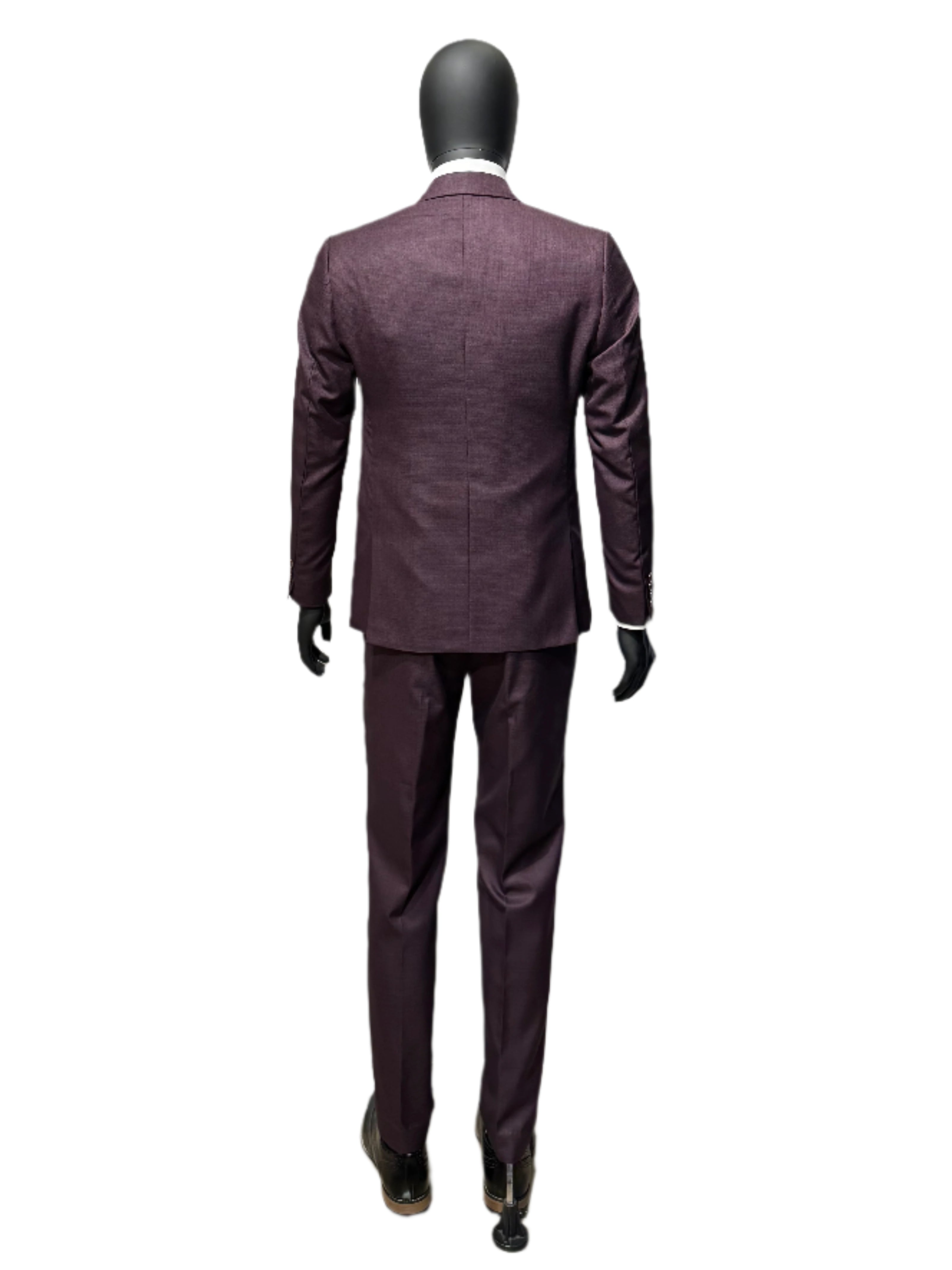 Mannequin wearing a dark suit in a store setting with brick wall background.