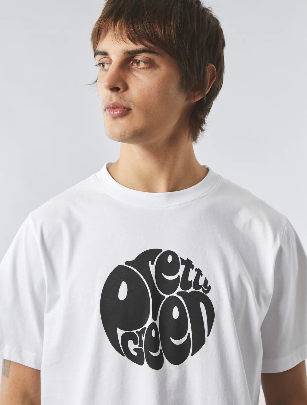 Person wearing a white t-shirt with a black graphic design on a plain background