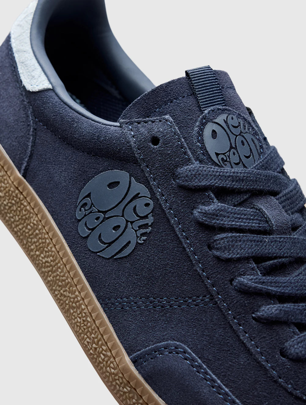 A navy-colored Pretty Green trainer with a suede upper, paisley graphic and logo, and a rubber gum outsole.