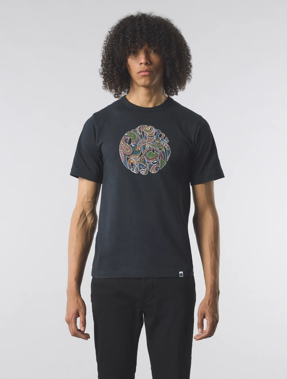 Person wearing a black t-shirt with a colorful circular design on a plain background