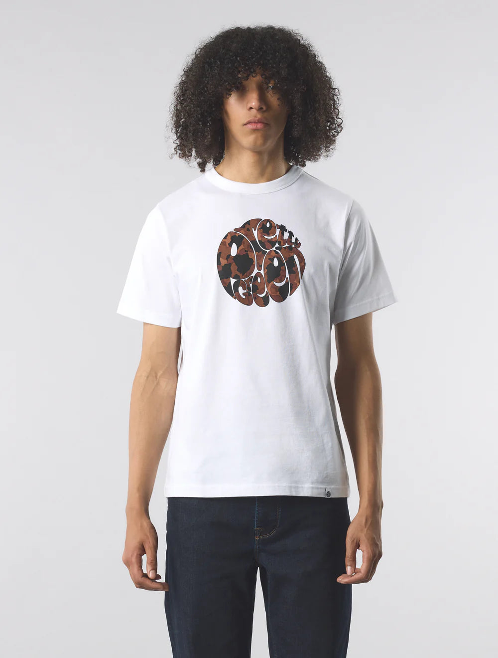 Person wearing a white t-shirt with a brown graphic design on a plain background