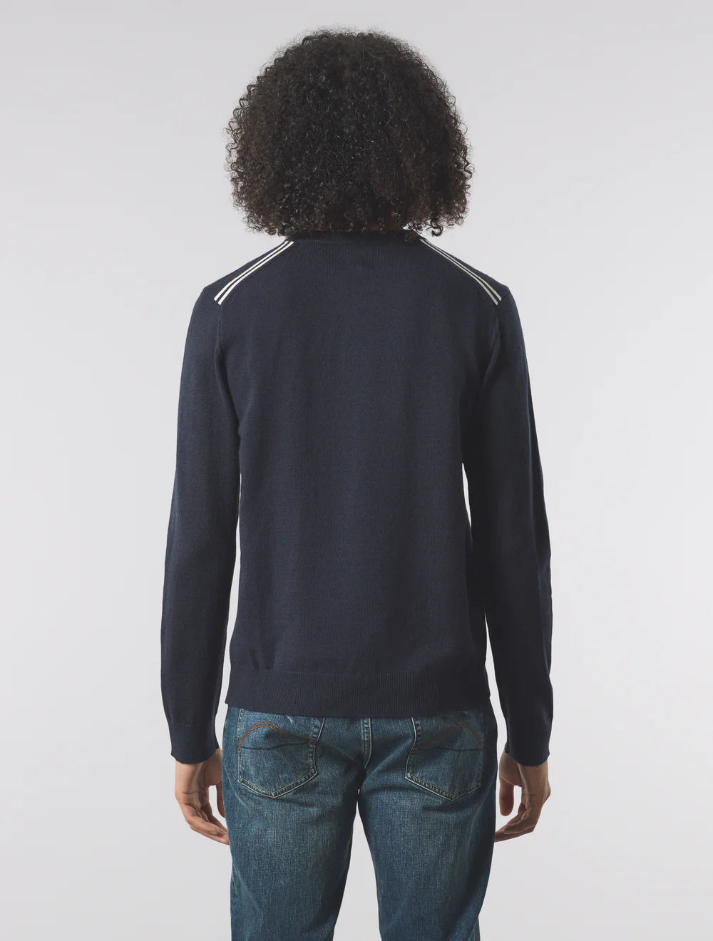 Person wearing a dark long-sleeve shirt with white stripes on a plain background