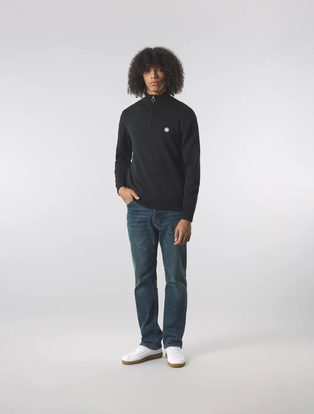 Person wearing a black long-sleeve shirt and blue jeans on a white background