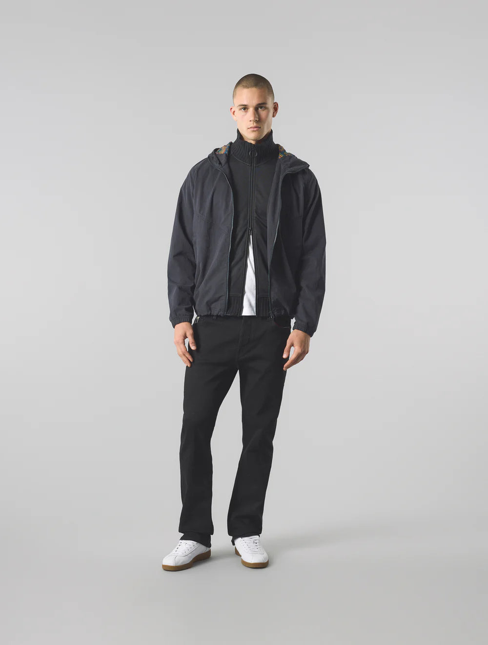 Man wearing a black jacket and pants on a gray background