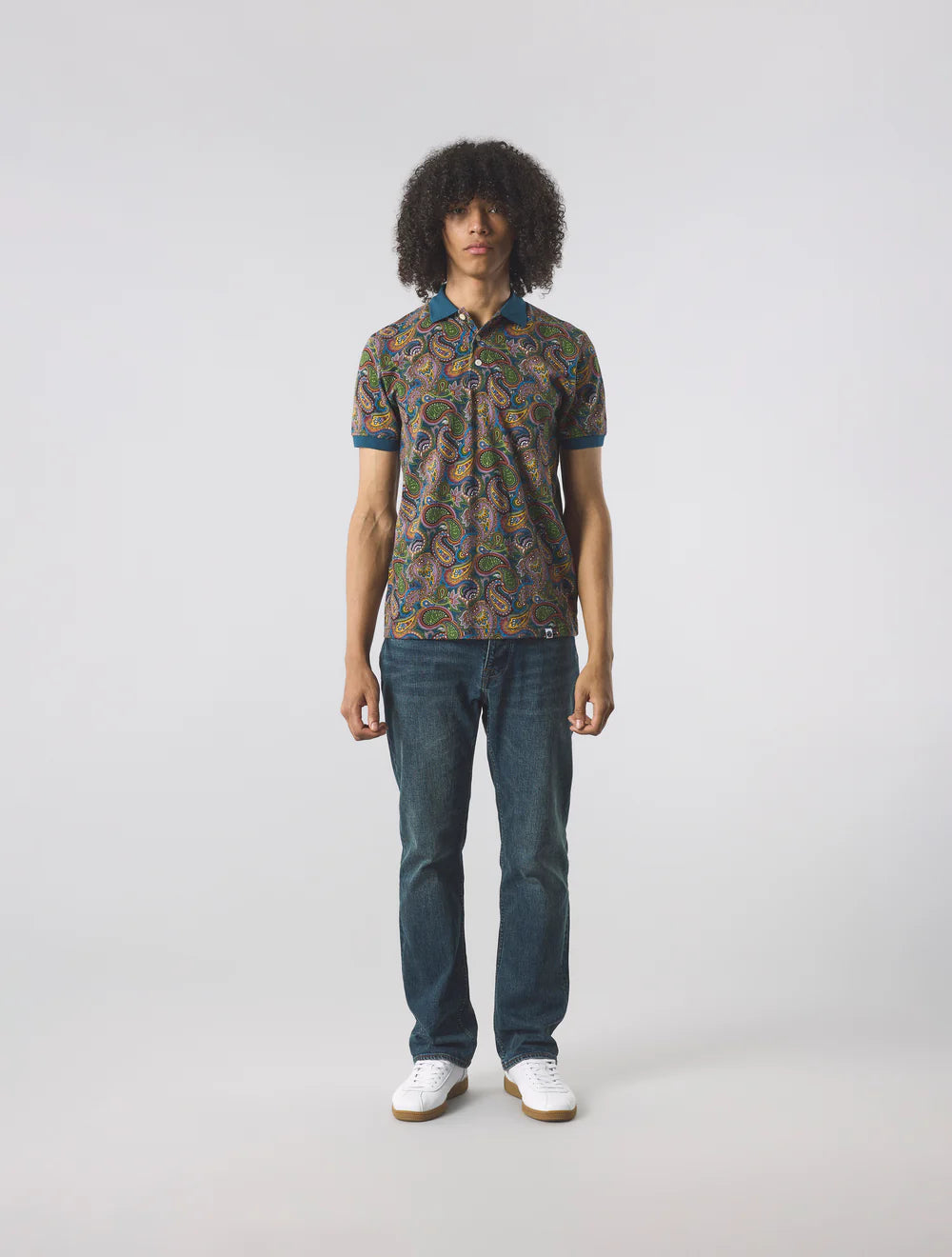 Person wearing a patterned shirt and jeans on a white background