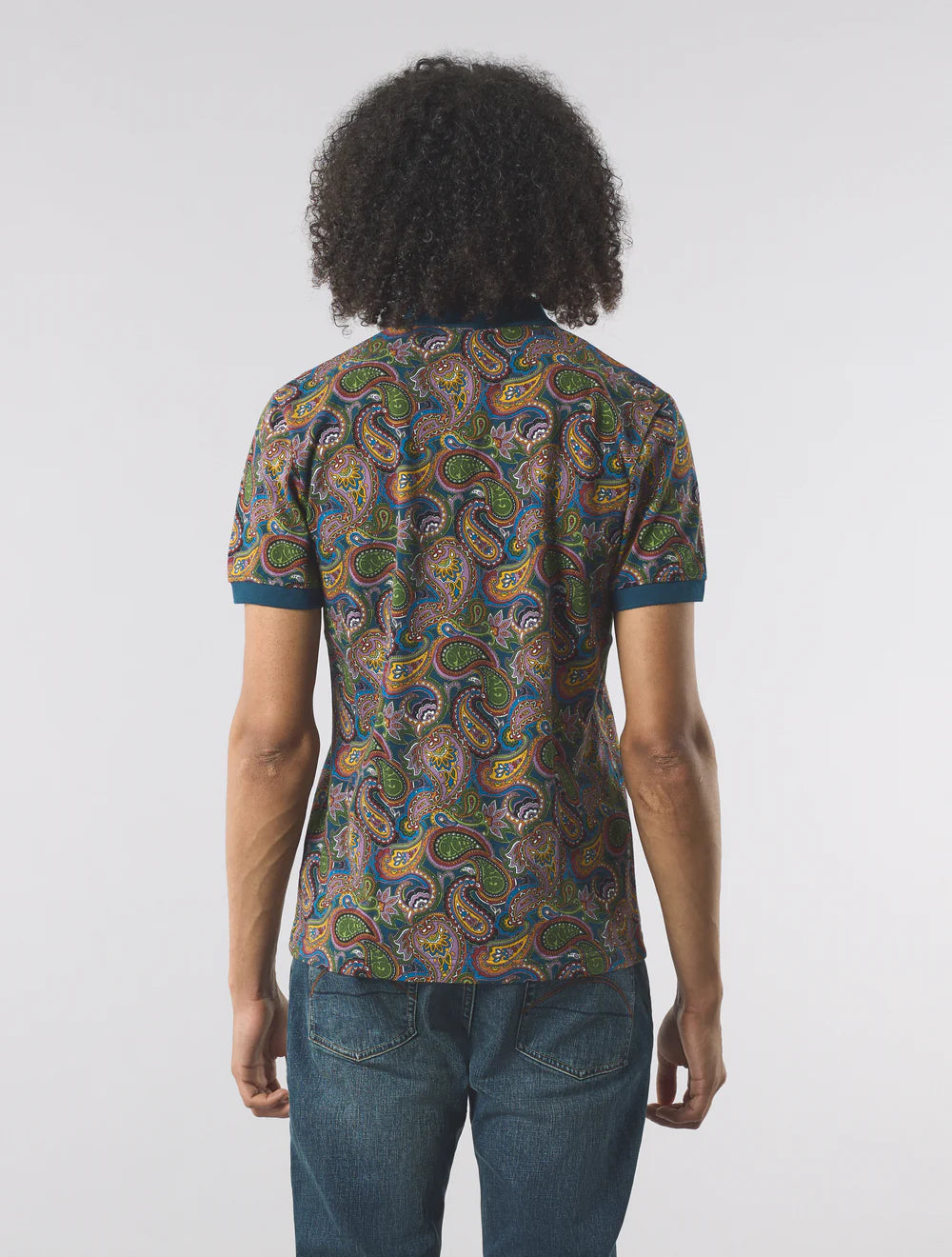 Person wearing a patterned shirt and jeans on a white background