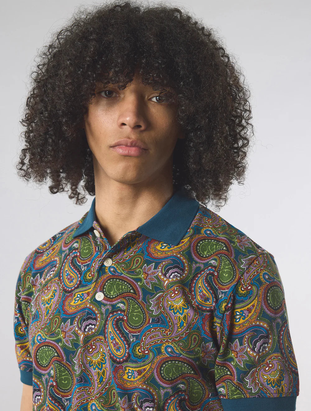 Person wearing a colorful paisley shirt against a plain background