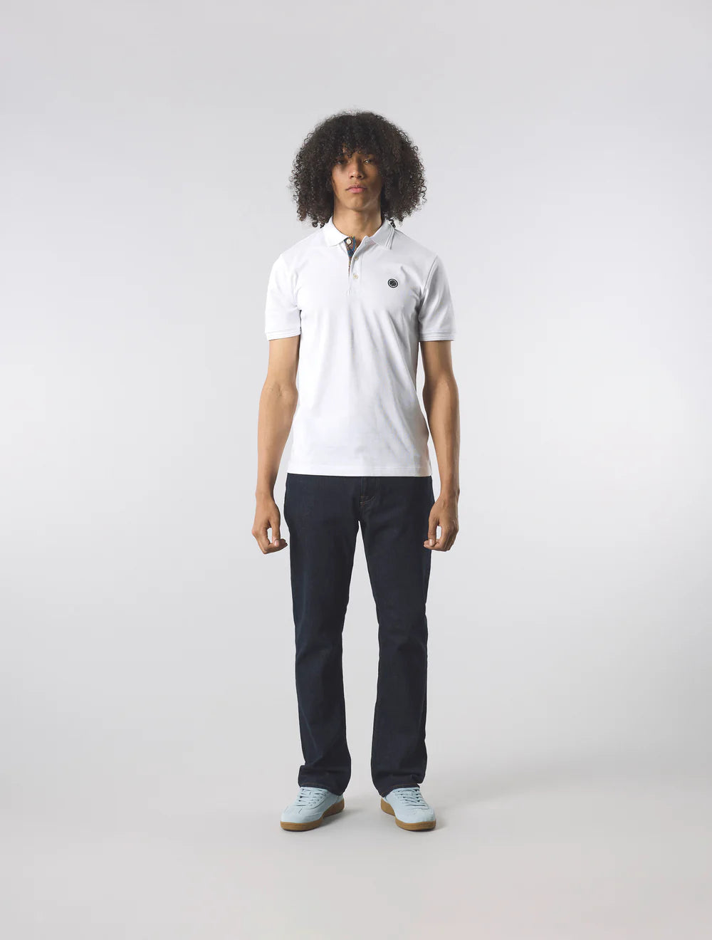 Person wearing a white polo shirt and dark pants on a light gray background