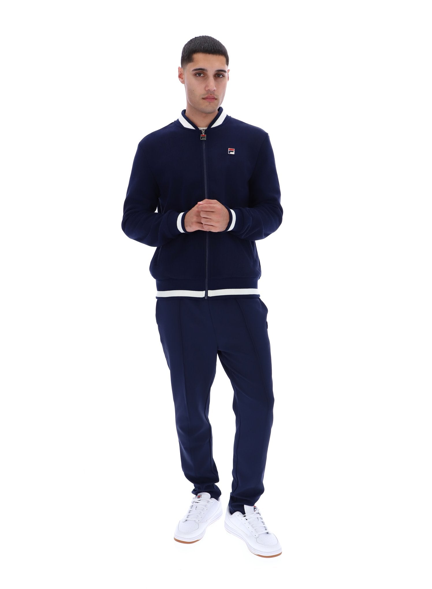 Man wearing a navy tracksuit with a white logo on a white background