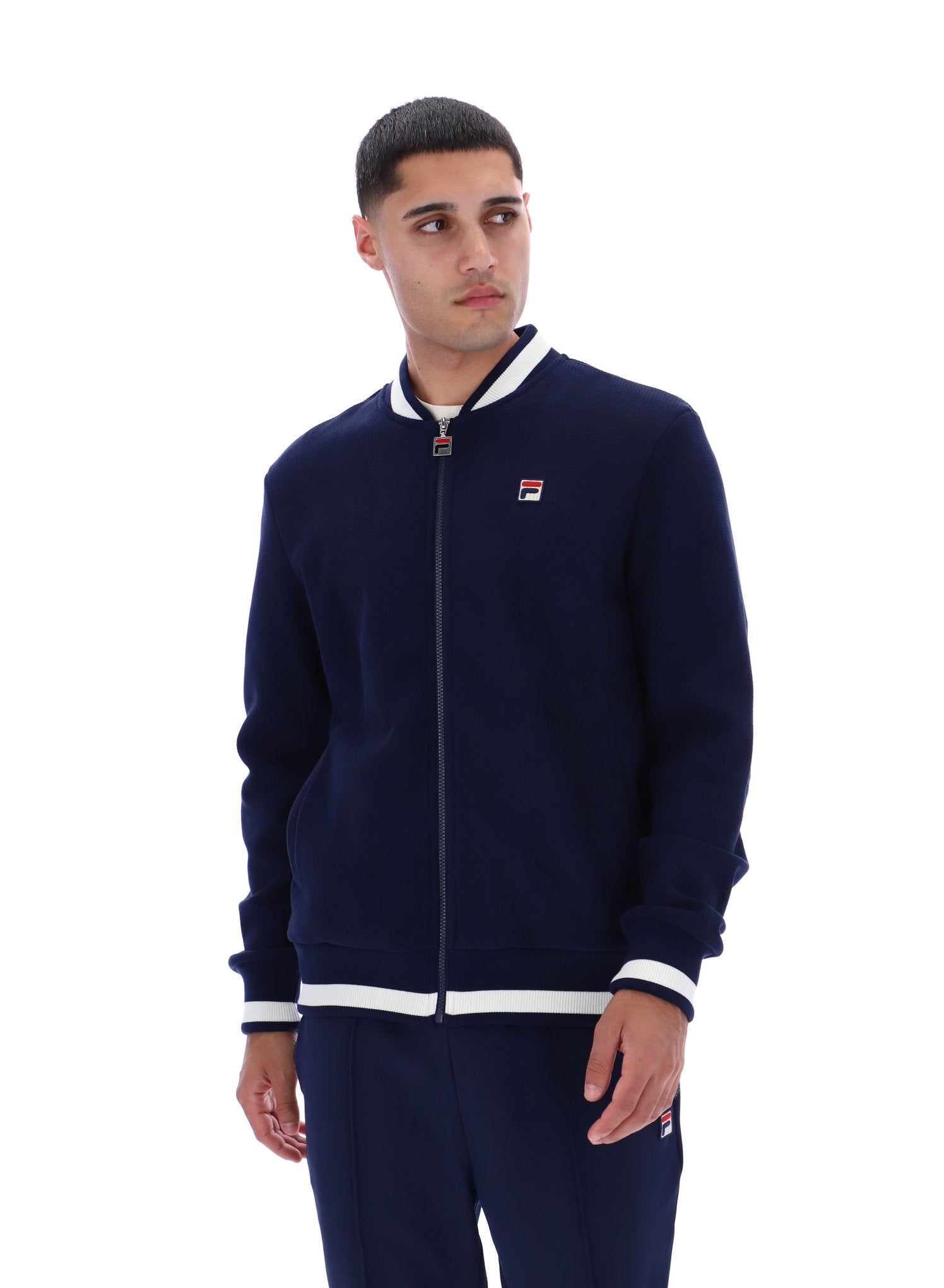Man wearing a navy tracksuit with white accents on a white background