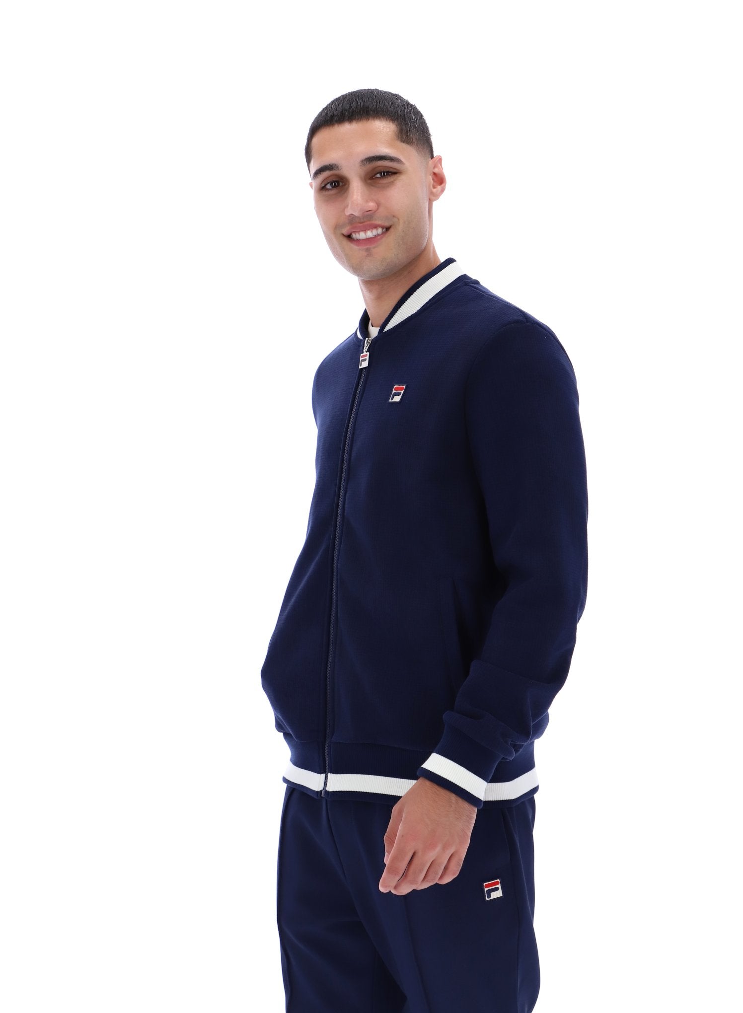Man wearing a navy tracksuit with white accents on a white background