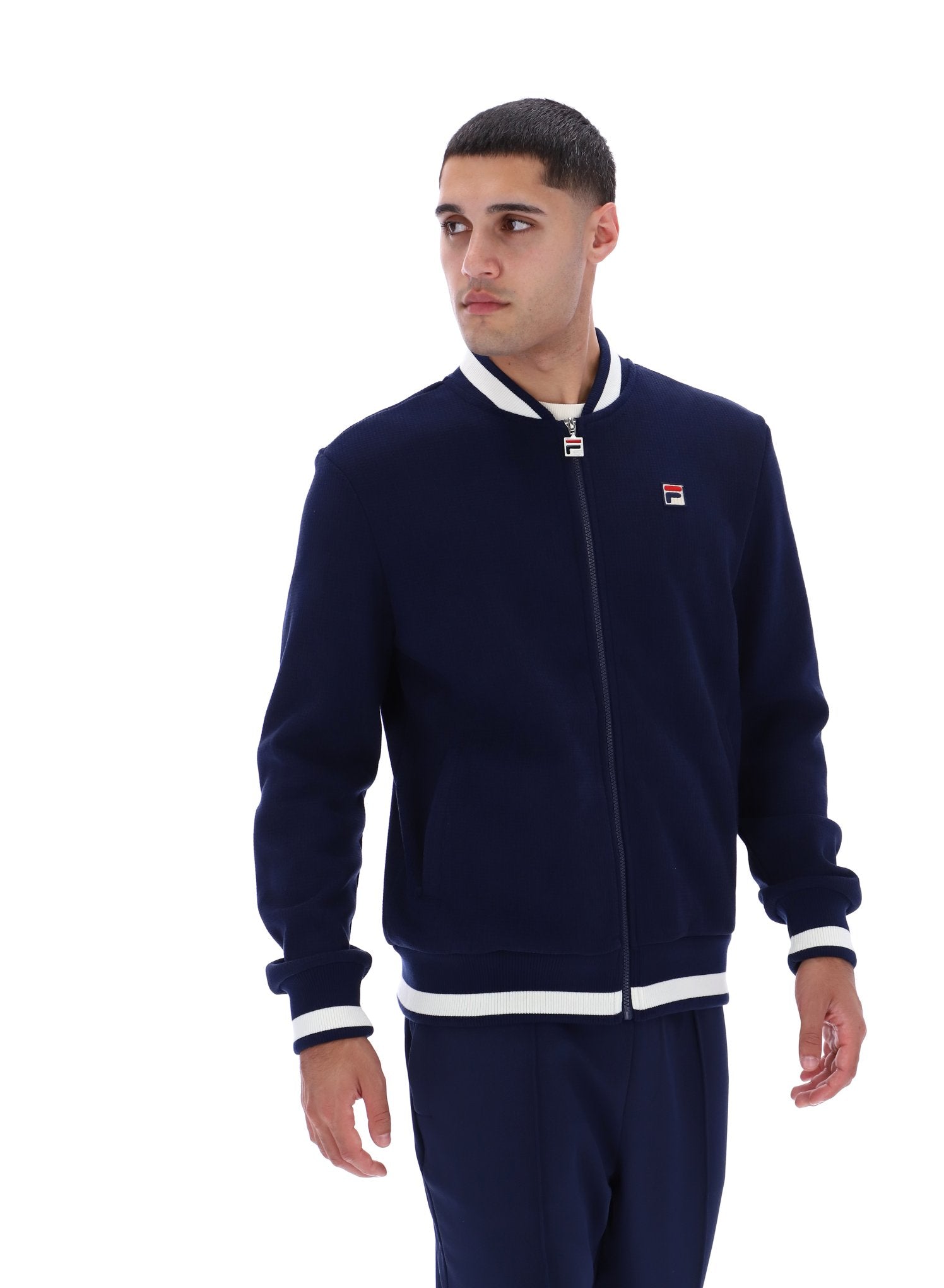 Man wearing a navy tracksuit with a brand logo on a white background