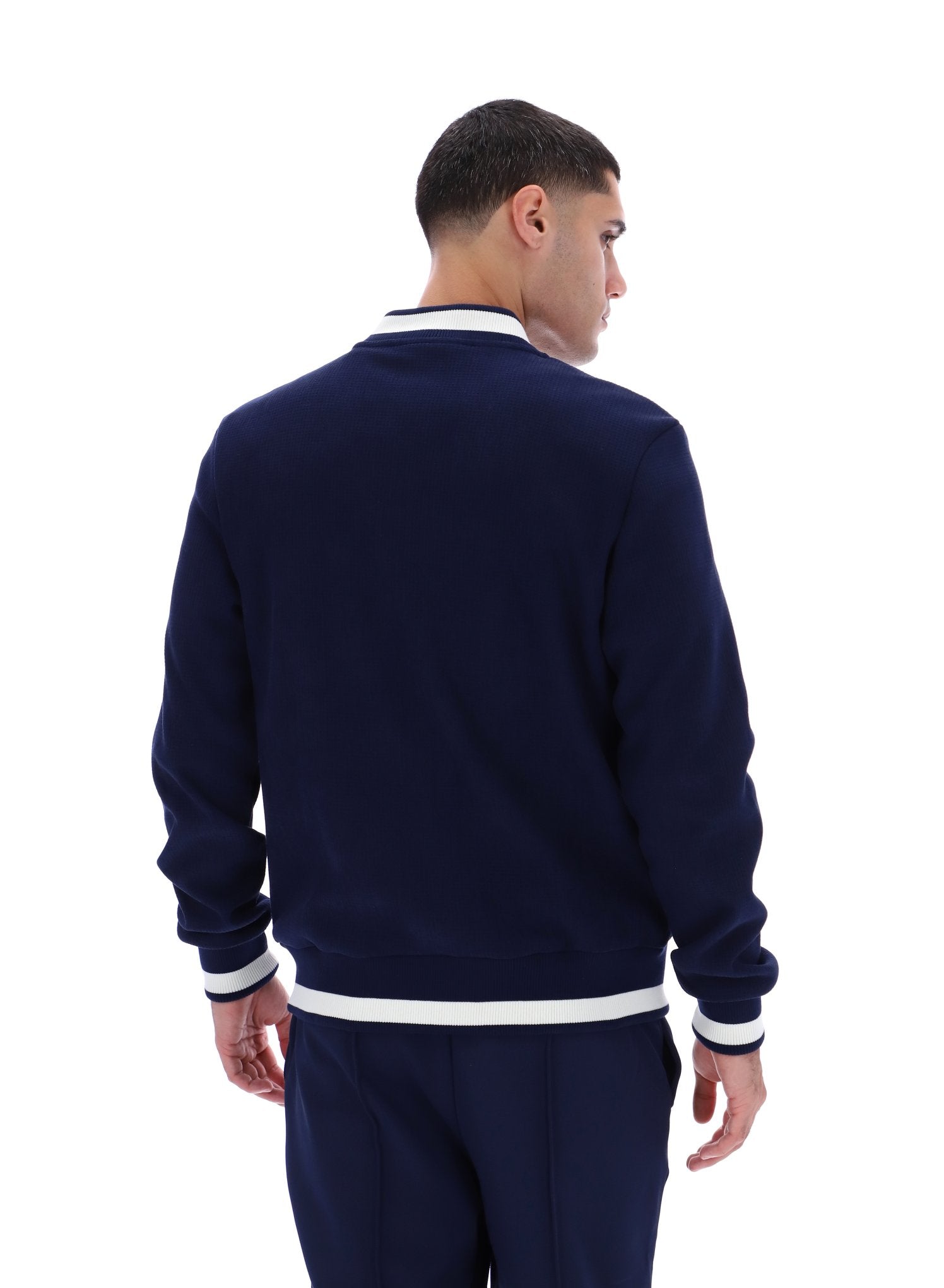 Man wearing a navy blue tracksuit with white trim on a white background