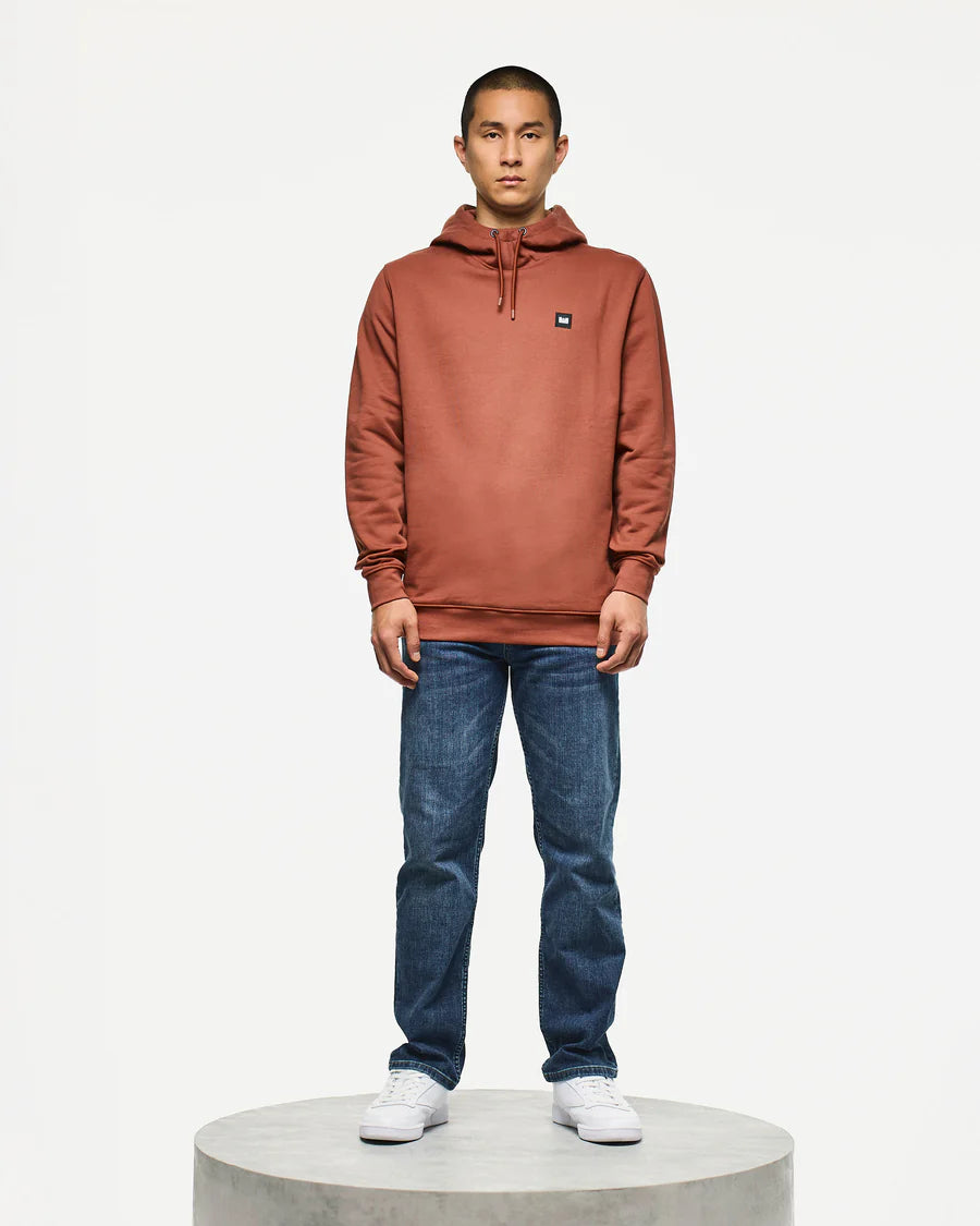 Man wearing a brown hoodie and blue jeans on a white background