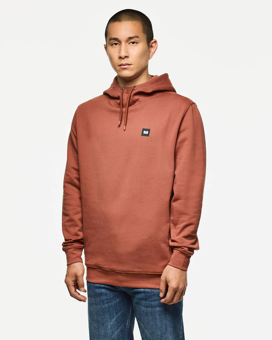 Man wearing a brown hoodie with a small logo on a white background