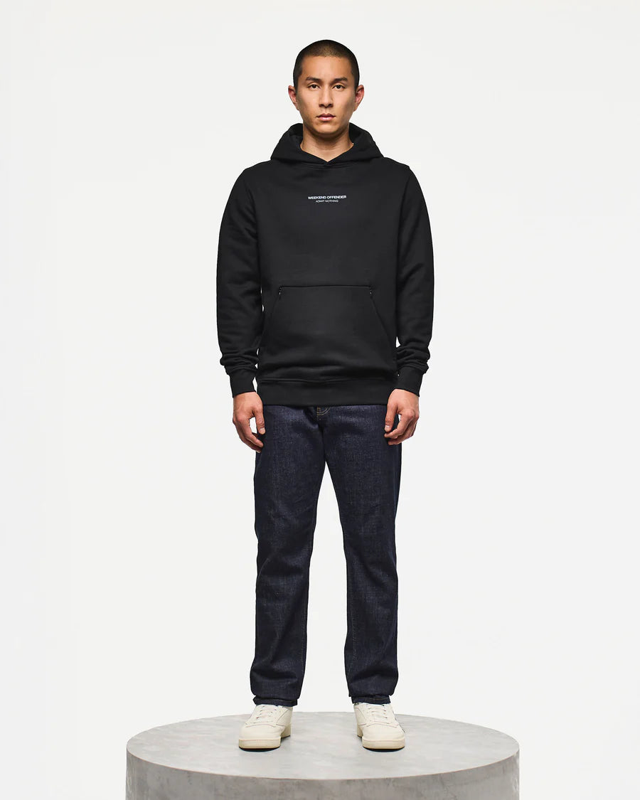 Person wearing a black hoodie and dark jeans on a white background