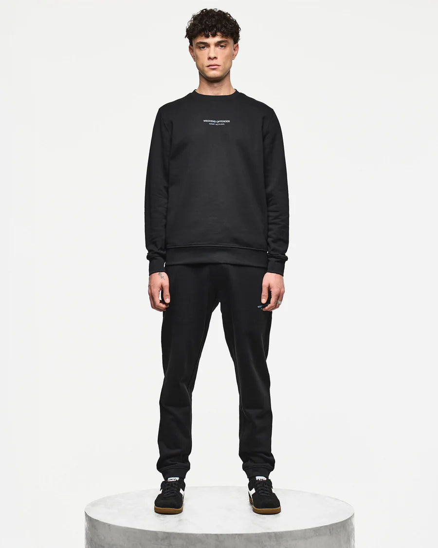 Person wearing a black sweatshirt and pants on a white background