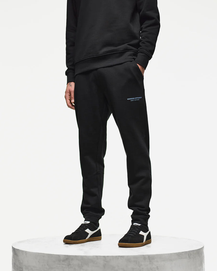 Person wearing a black tracksuit with a brand logo on a white background