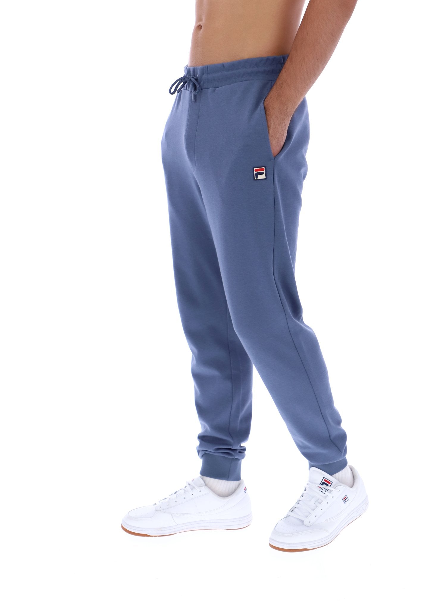 Person wearing blue jogger pants with a visible brand logo on a white background