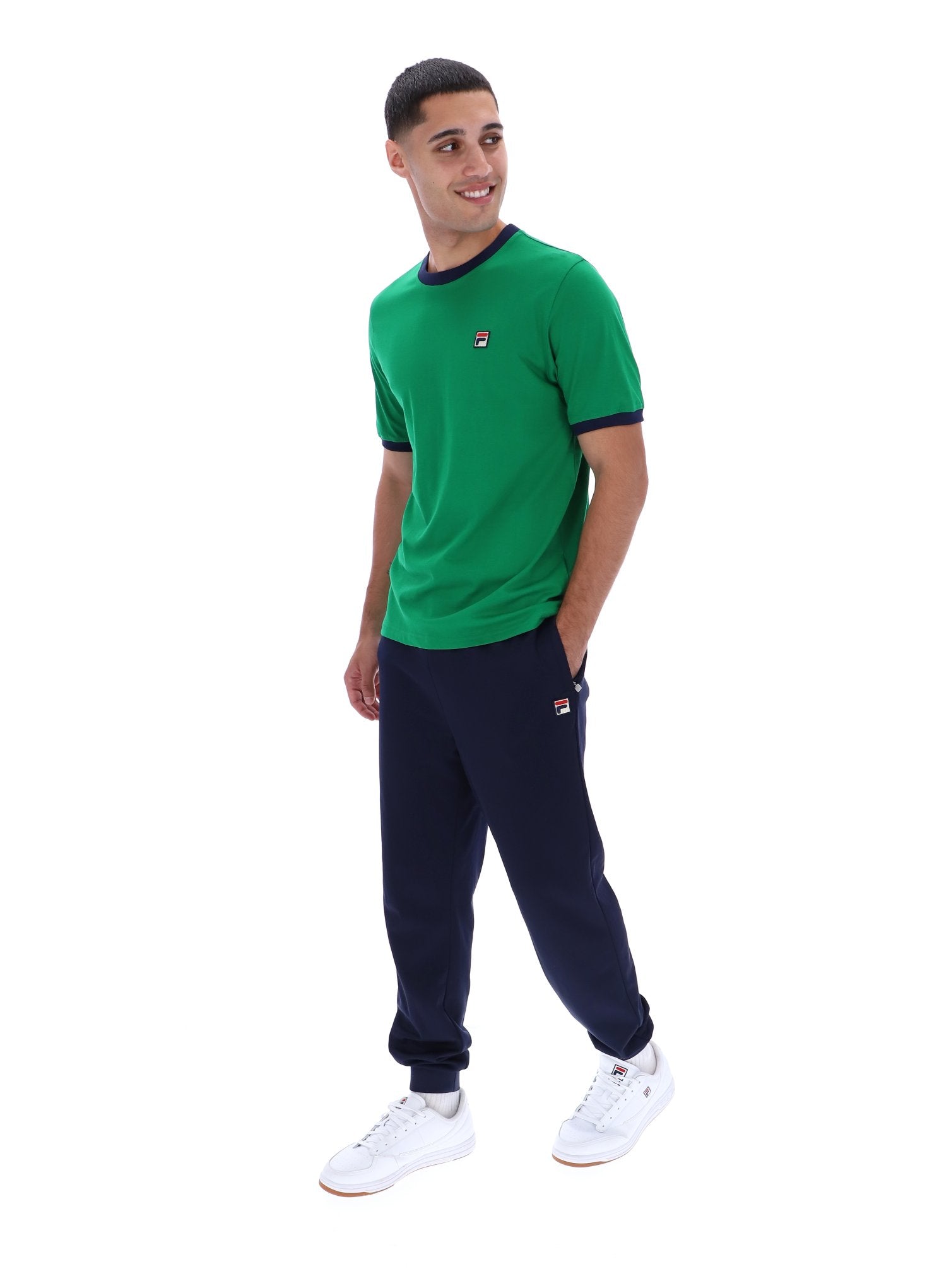 Man wearing a green t-shirt and navy tracksuit on a white background