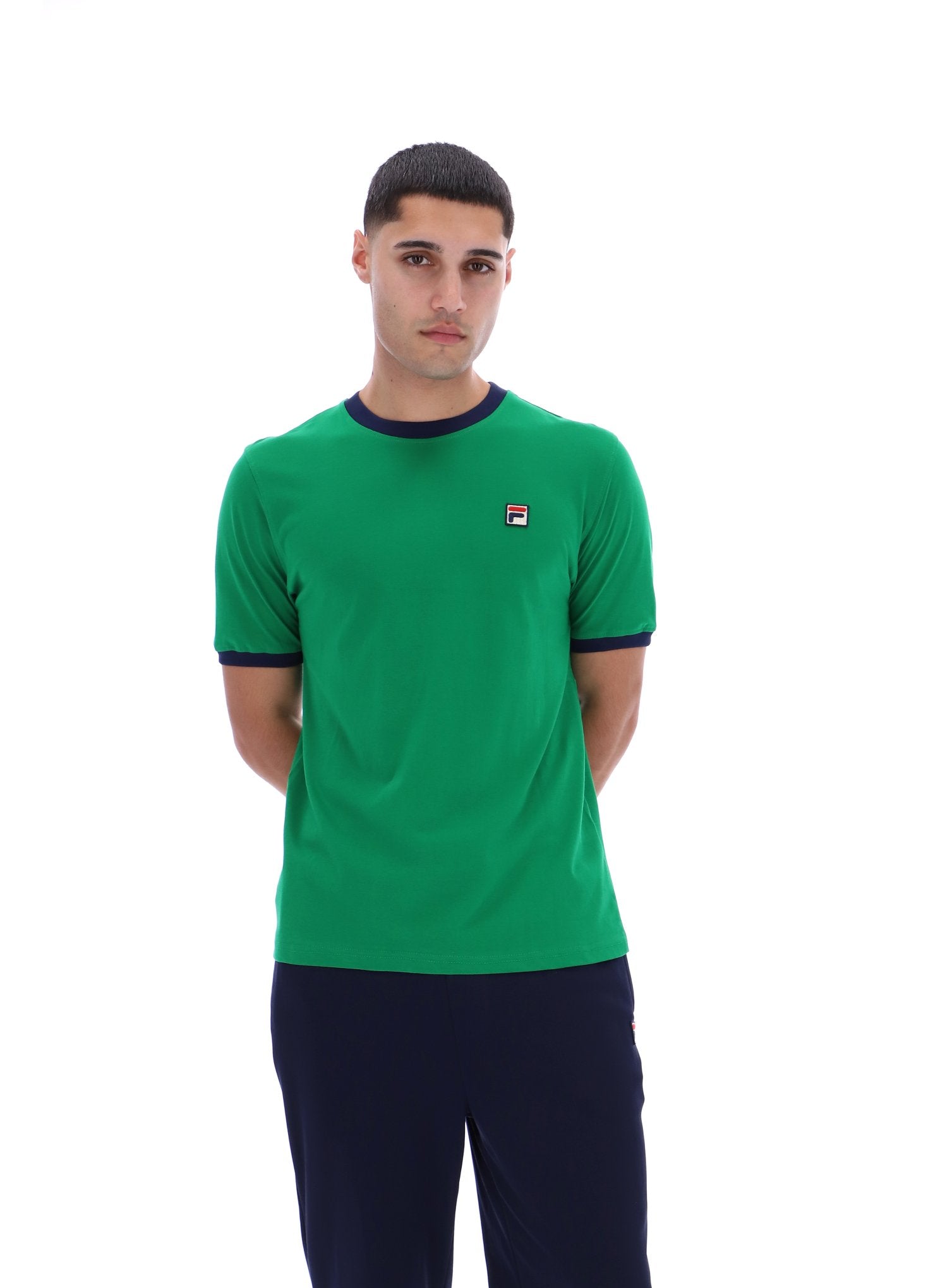 Man wearing a green t-shirt with a small logo on a white background