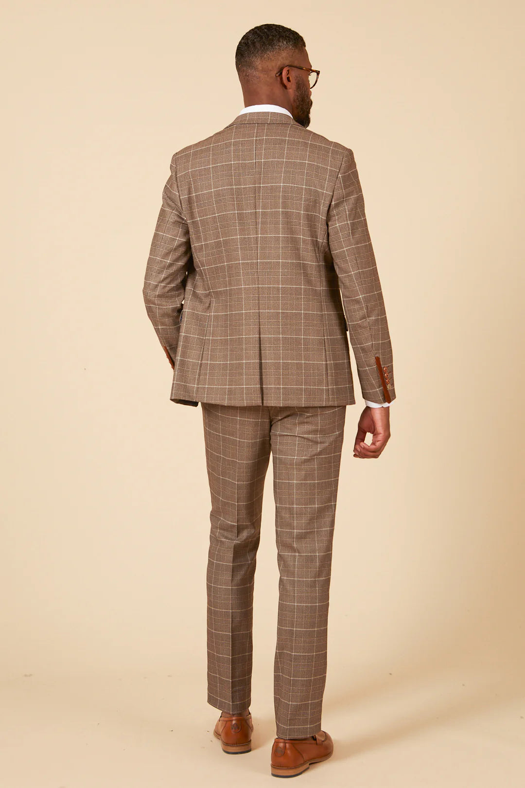 Man wearing a brown checkered suit against a beige background