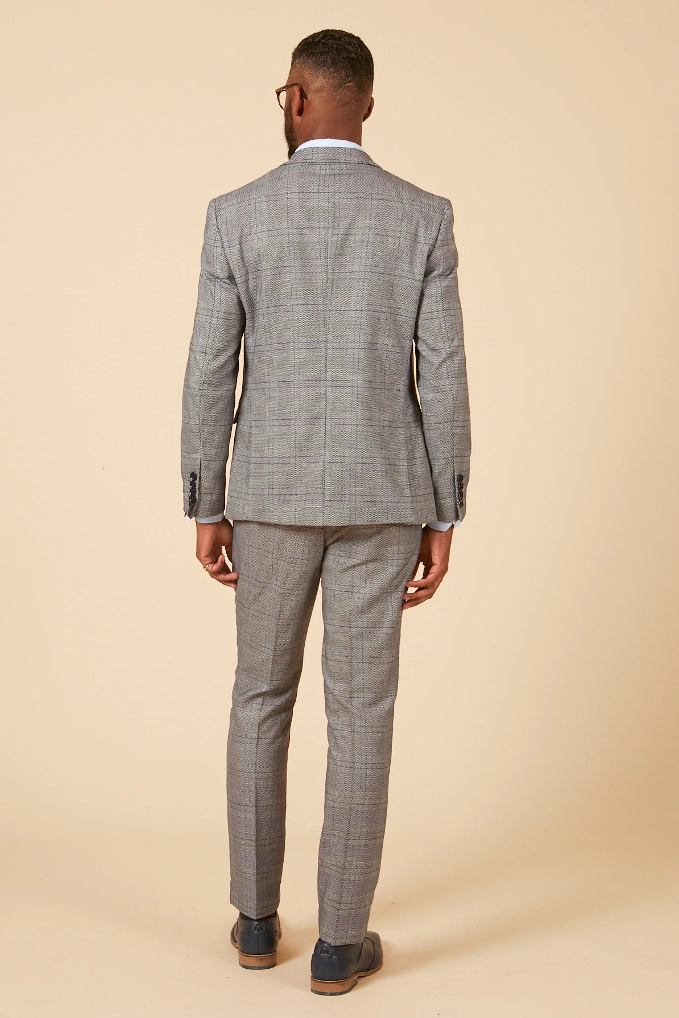 Person wearing a gray checkered suit on a beige background