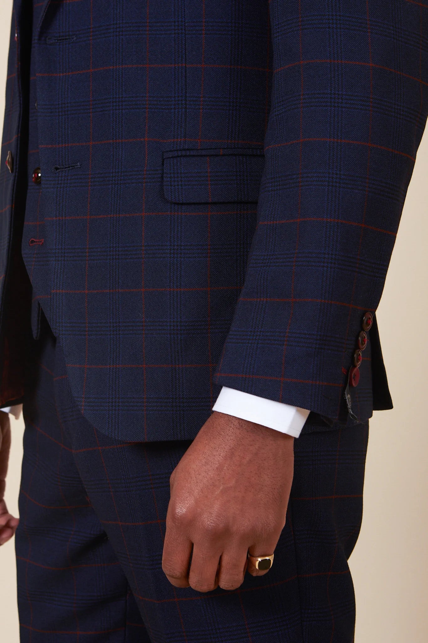 Close-up of a person wearing a navy blue suit with red check pattern.