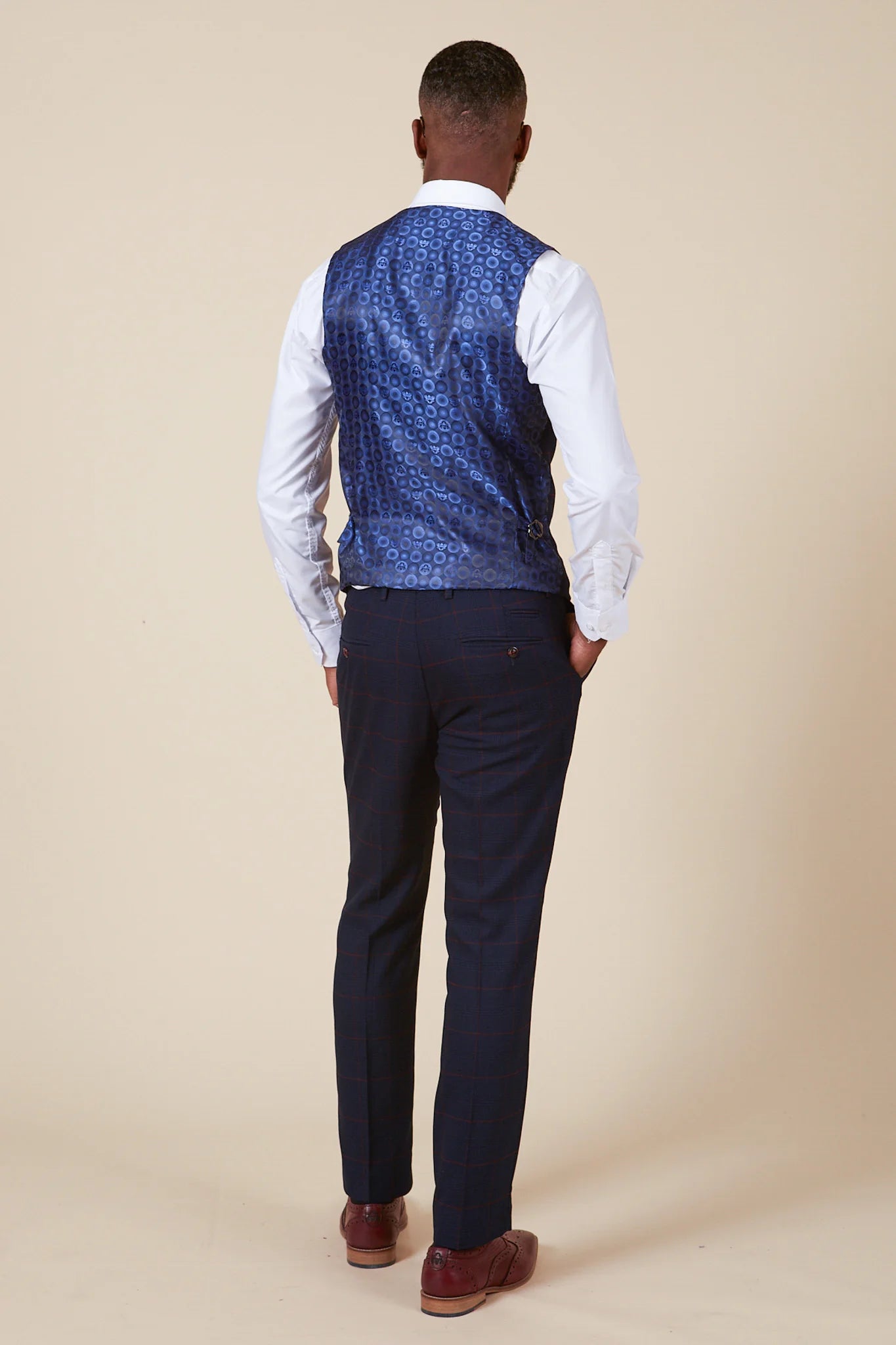 Person wearing a blue patterned vest over a white shirt and dark blue pants.