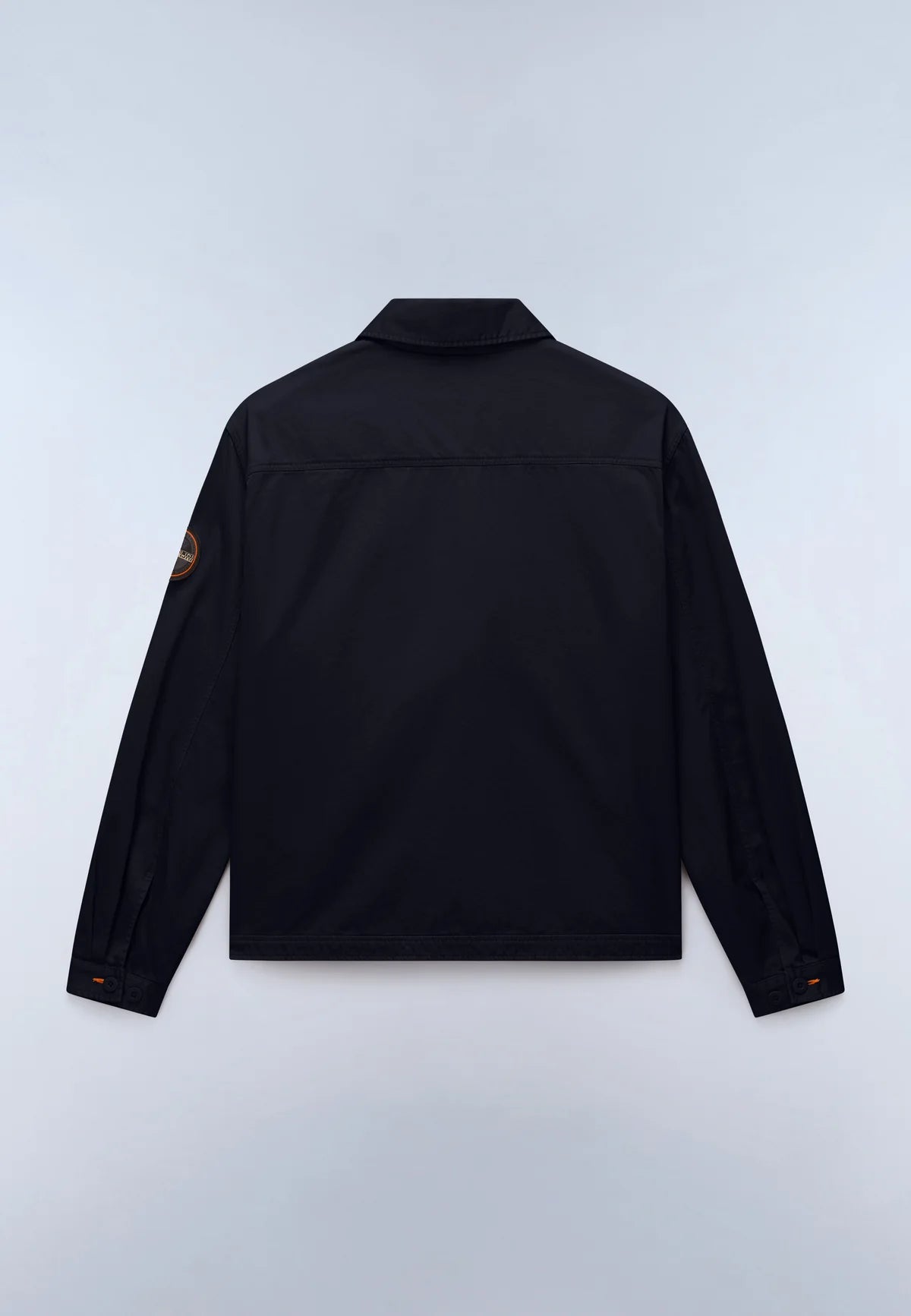 A black long-sleeve jacket shown from the back, featuring a small brown circular logo patch on the left sleeve, laid flat against a light gray background.